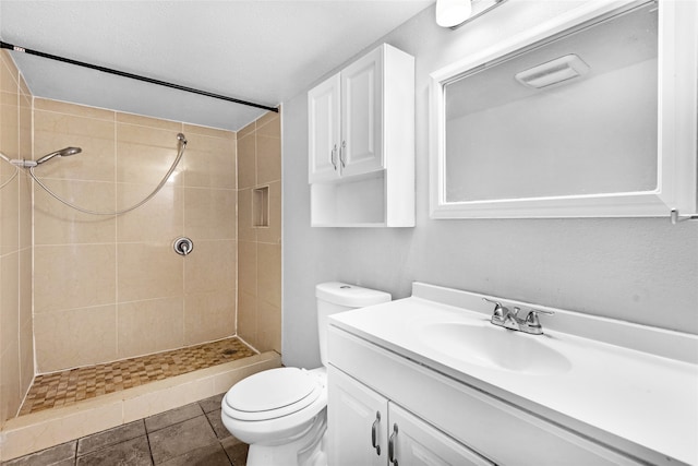 bathroom with vanity, tile patterned flooring, toilet, and a tile shower