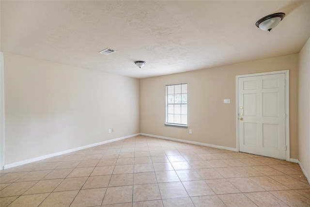 unfurnished room featuring a textured ceiling and light tile patterned floors