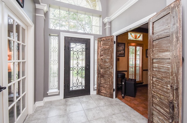 foyer entrance featuring light tile patterned flooring, french doors, and crown molding