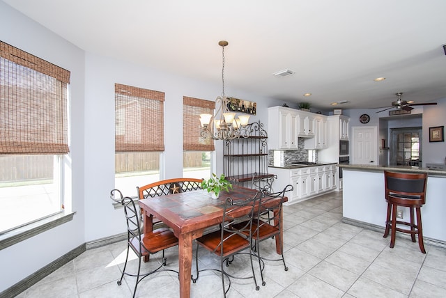 dining area featuring light tile patterned floors, a healthy amount of sunlight, and ceiling fan with notable chandelier