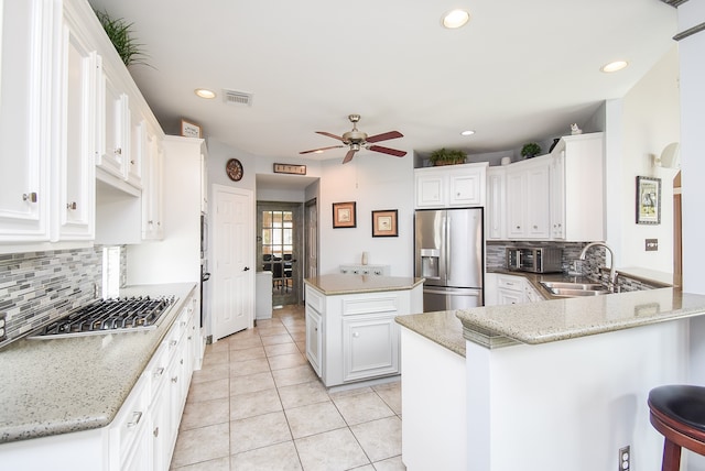 kitchen with white cabinets, stainless steel appliances, and light stone counters