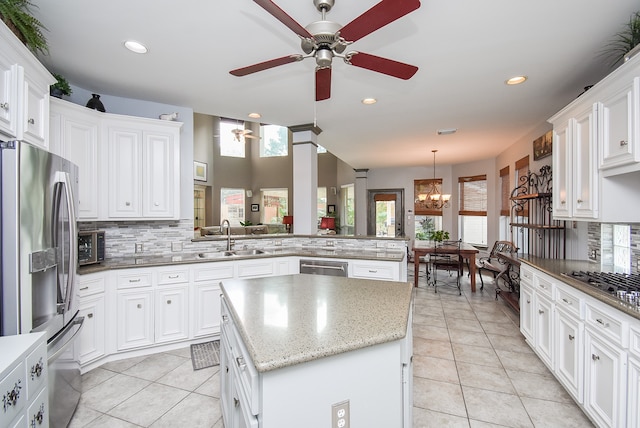 kitchen with kitchen peninsula, plenty of natural light, sink, a kitchen island, and appliances with stainless steel finishes