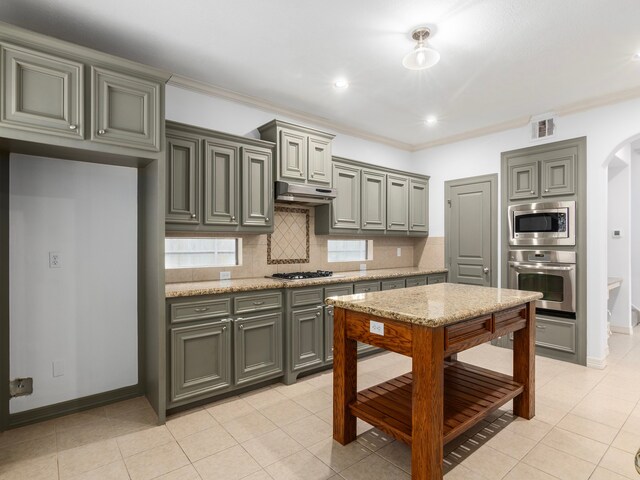 kitchen featuring appliances with stainless steel finishes, light tile patterned floors, tasteful backsplash, and light stone countertops