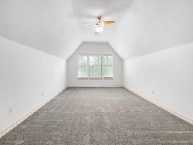 additional living space with a textured ceiling, carpet, ceiling fan, and vaulted ceiling