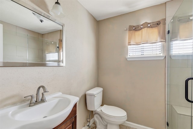 bathroom with toilet, vanity, and a shower with shower door