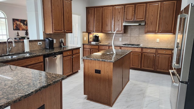 kitchen featuring sink, a center island, tasteful backsplash, dark stone counters, and appliances with stainless steel finishes