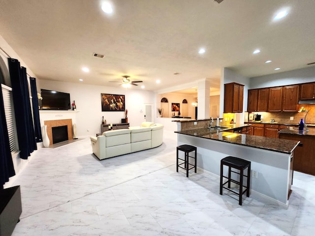 kitchen featuring backsplash, sink, ceiling fan, a kitchen bar, and kitchen peninsula