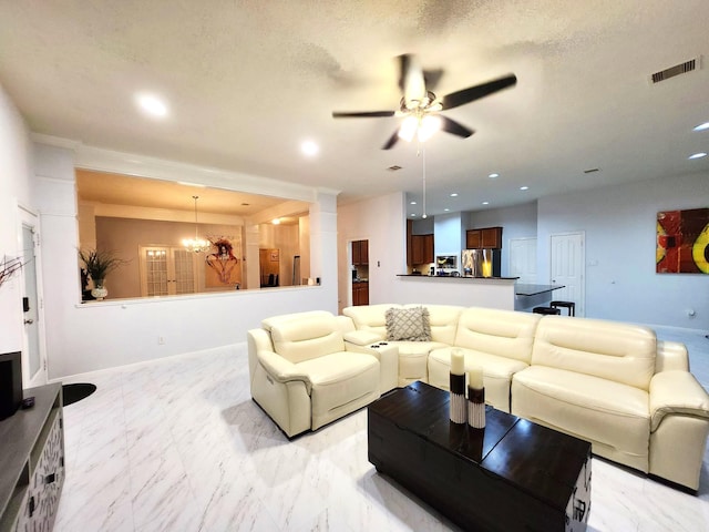 living room with ceiling fan with notable chandelier and a textured ceiling