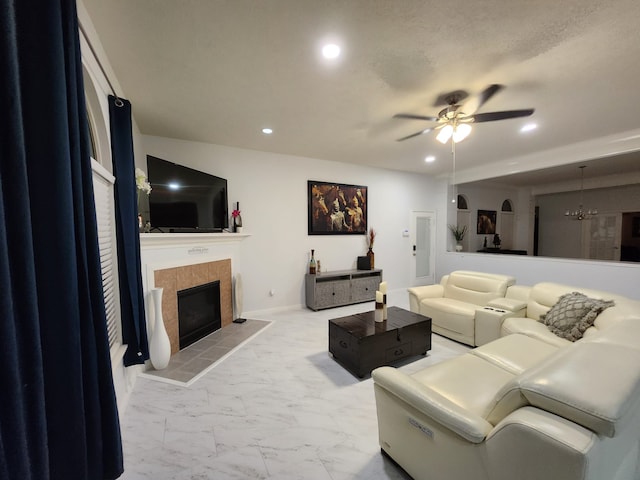 living room featuring a fireplace and ceiling fan with notable chandelier