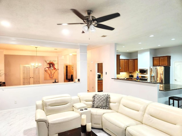 living room featuring ceiling fan with notable chandelier and a textured ceiling