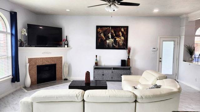 living room with a tile fireplace and ceiling fan