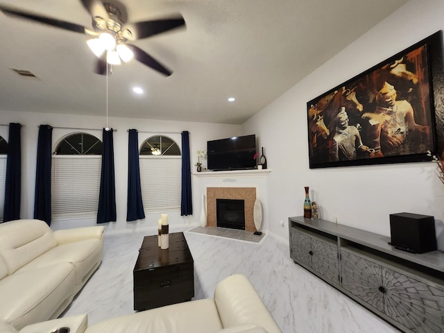 living room with a tile fireplace and ceiling fan