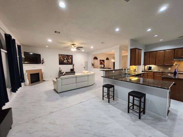 kitchen featuring a breakfast bar, sink, ceiling fan, tasteful backsplash, and kitchen peninsula