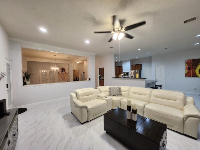 living room featuring ceiling fan with notable chandelier and a textured ceiling