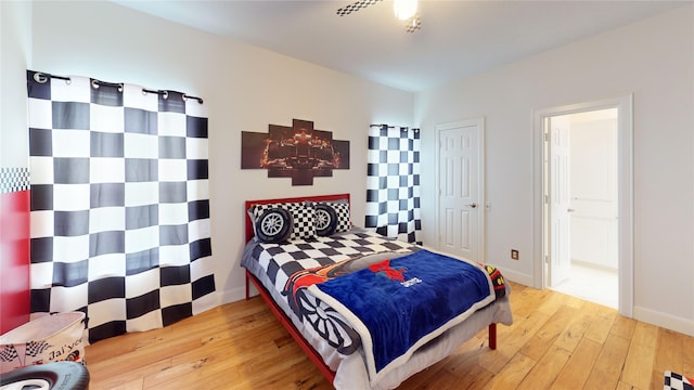 bedroom featuring baseboards, ensuite bathroom, vaulted ceiling, and hardwood / wood-style flooring