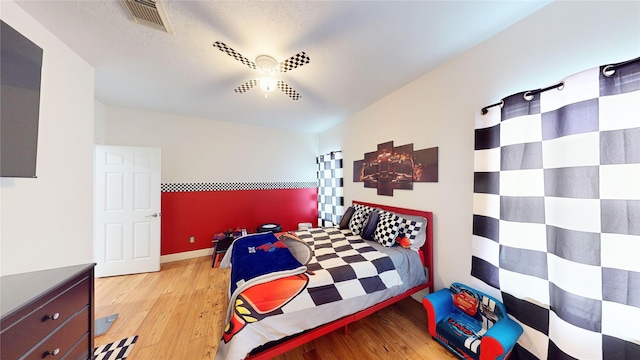 bedroom with wood finished floors, visible vents, and a textured ceiling