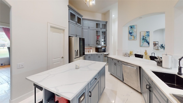 kitchen with a breakfast bar area, gray cabinets, sink, and stainless steel appliances