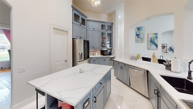 4009 Ravencrest Ct, Pearland, TX 77584 - kitchen with gray cabinets, stainless steel appliances, a sink, arched walkways, and a center island