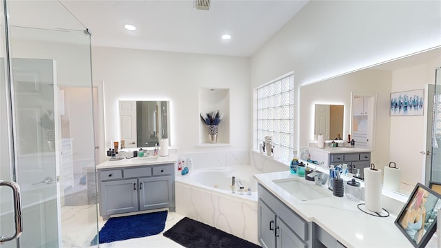 full bathroom featuring visible vents, two vanities, a sink, a shower stall, and a garden tub