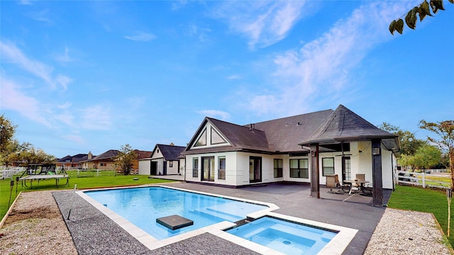 outdoor pool with an in ground hot tub, a yard, a patio area, and fence