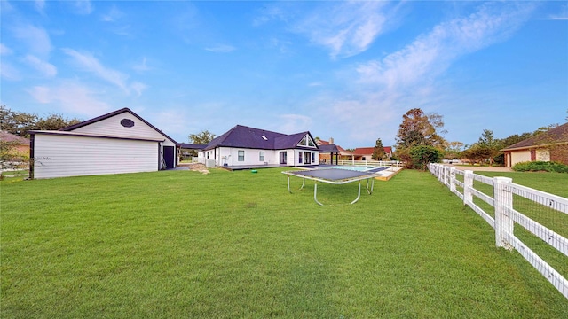 view of yard featuring an outdoor structure, a garage, and a trampoline