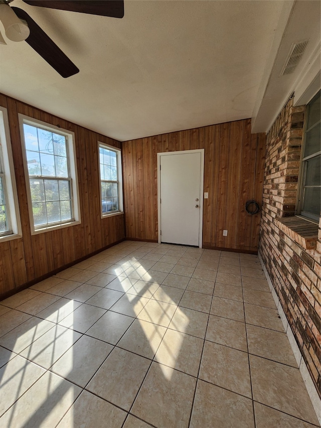 interior space with wooden walls, light tile patterned floors, and ceiling fan