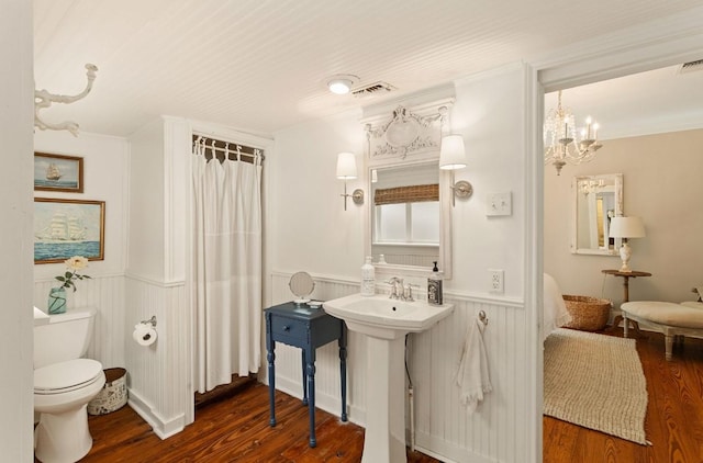 full bath with visible vents, crown molding, a wainscoted wall, toilet, and wood finished floors