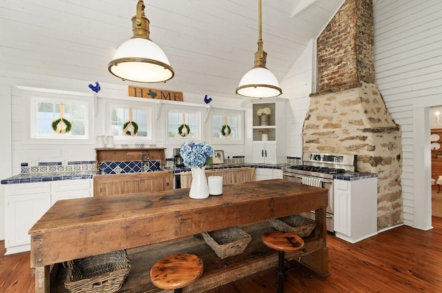 kitchen featuring double oven range, lofted ceiling, dark wood-style flooring, hanging light fixtures, and white cabinetry