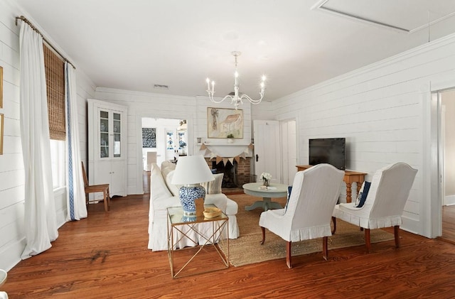 interior space with an inviting chandelier, ornamental molding, wood-type flooring, and a fireplace