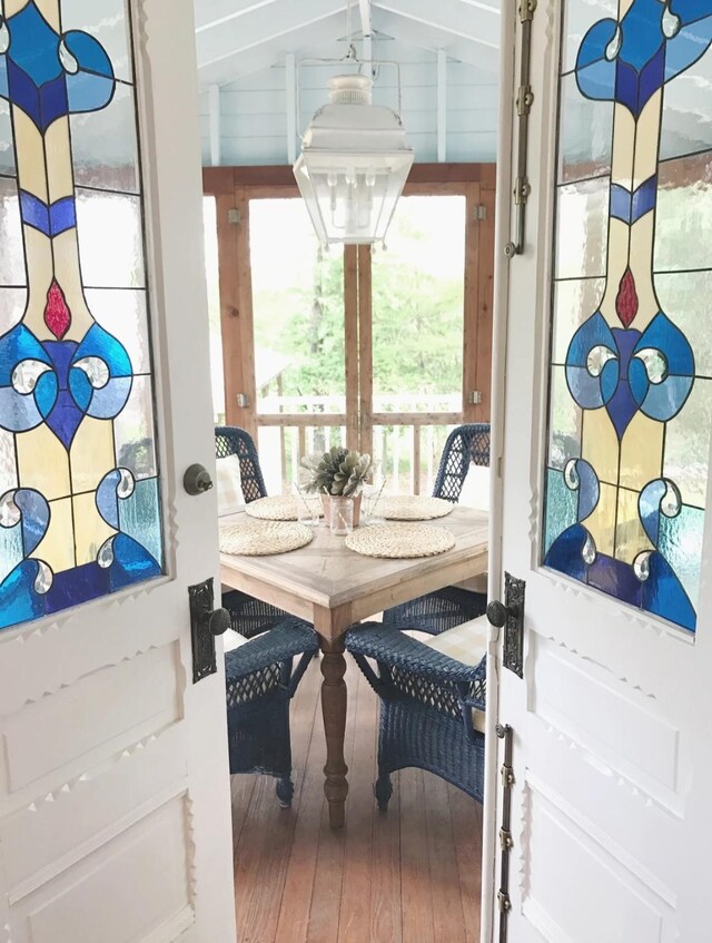 dining area featuring breakfast area, wood-type flooring, and vaulted ceiling