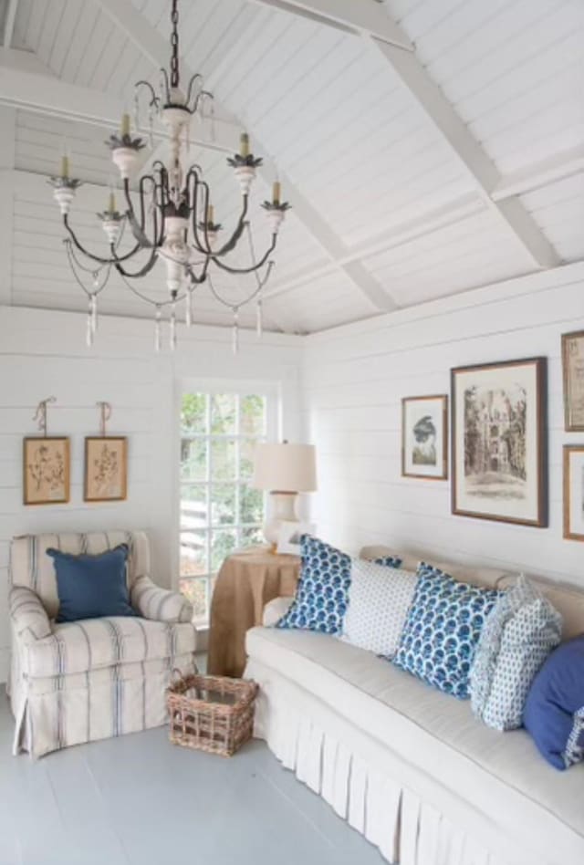 living room with wooden walls, vaulted ceiling with beams, and an inviting chandelier