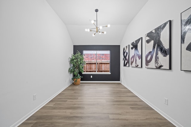 spare room featuring lofted ceiling, hardwood / wood-style flooring, and a notable chandelier