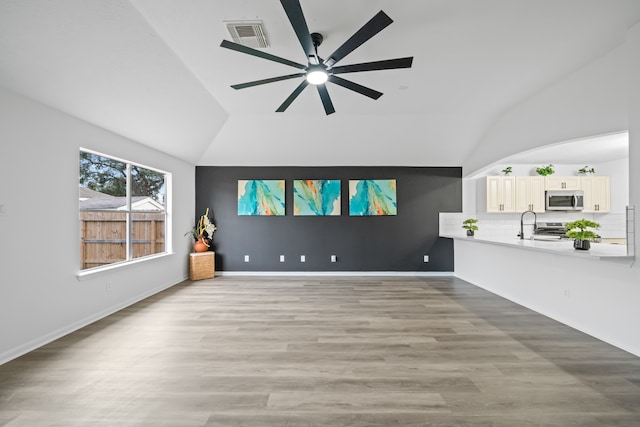 unfurnished living room featuring light hardwood / wood-style flooring, lofted ceiling, and ceiling fan