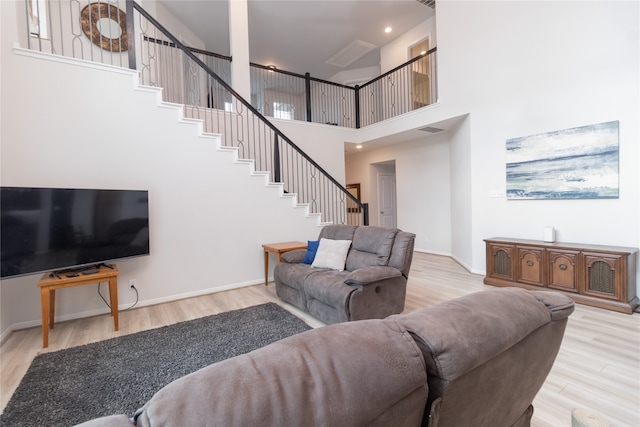 living room featuring light wood-type flooring and a towering ceiling