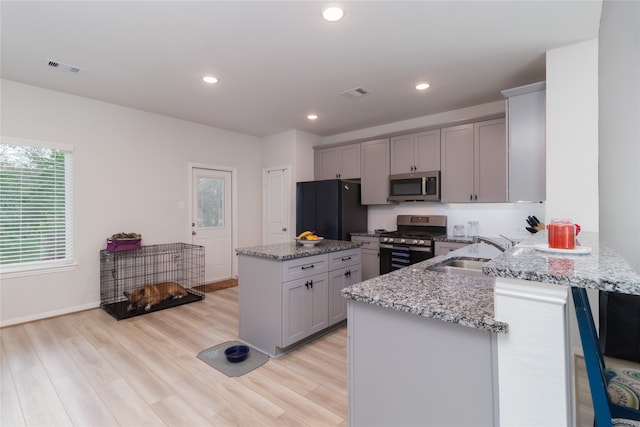 kitchen featuring kitchen peninsula, stainless steel appliances, a wealth of natural light, and light stone countertops