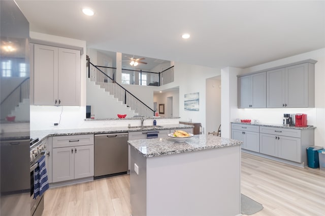 kitchen featuring stainless steel appliances, a kitchen island, light hardwood / wood-style floors, kitchen peninsula, and ceiling fan