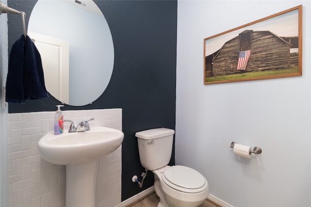 bathroom featuring decorative backsplash and toilet