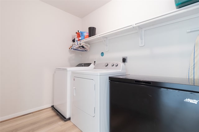 clothes washing area with independent washer and dryer and light hardwood / wood-style floors