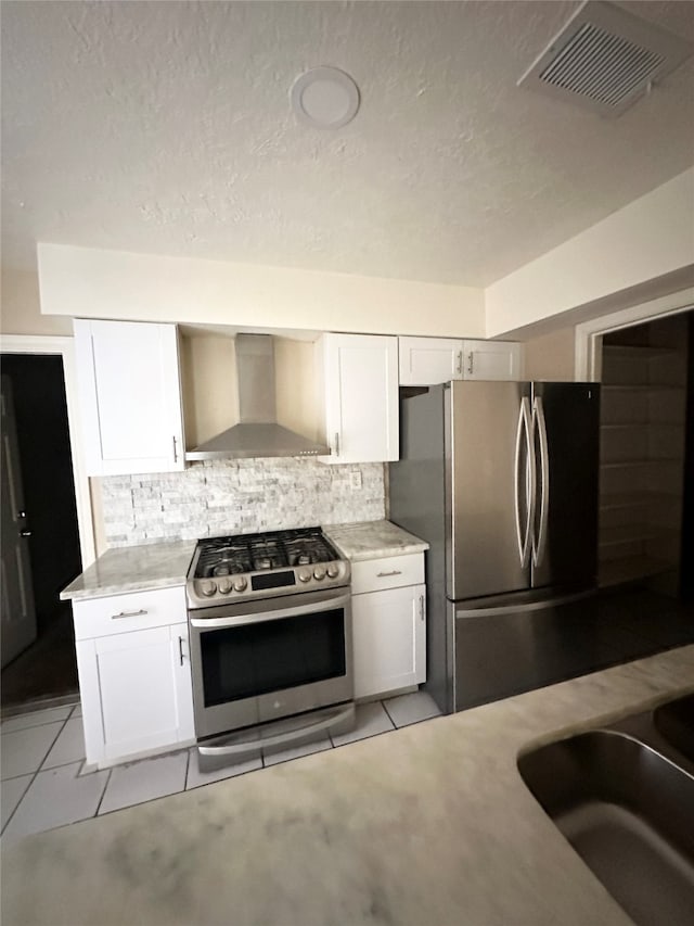 kitchen with wall chimney range hood, appliances with stainless steel finishes, backsplash, and white cabinets