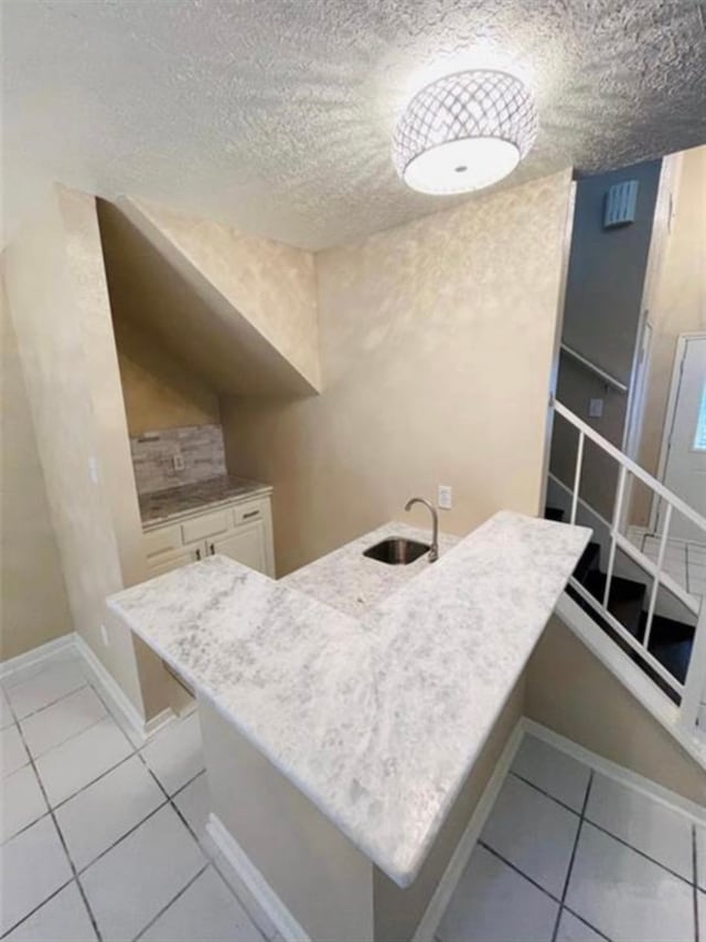 kitchen with white cabinets, a textured ceiling, and light tile patterned floors