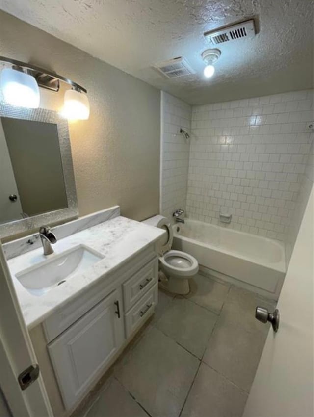 full bathroom with tiled shower / bath, vanity, a textured ceiling, and tile patterned flooring