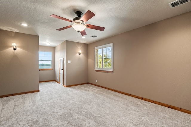 empty room featuring baseboards, a textured ceiling, visible vents, and light colored carpet