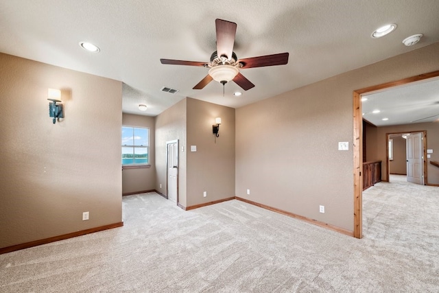 unfurnished room with visible vents, ceiling fan, light carpet, and baseboards