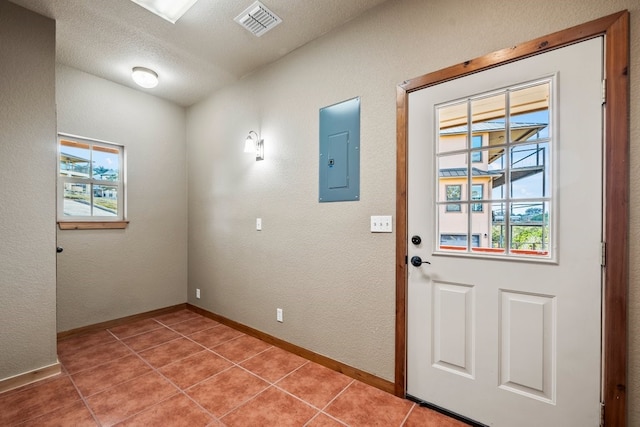 interior space featuring light tile patterned floors, a textured ceiling, visible vents, baseboards, and electric panel