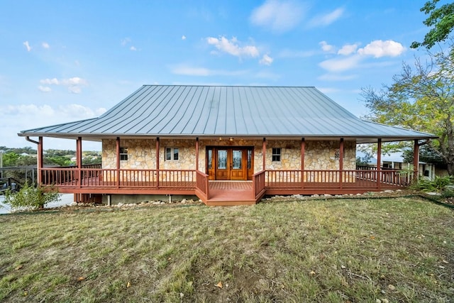 rear view of house featuring stone siding, a standing seam roof, a yard, and metal roof