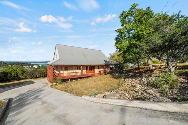 farmhouse inspired home with a front yard, covered porch, and driveway