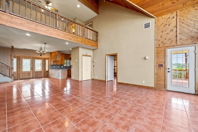 unfurnished living room with visible vents, tile patterned floors, wood walls, a notable chandelier, and recessed lighting