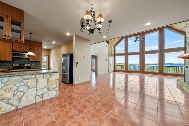 kitchen with light tile patterned floors, tasteful backsplash, brown cabinetry, appliances with stainless steel finishes, and hanging light fixtures