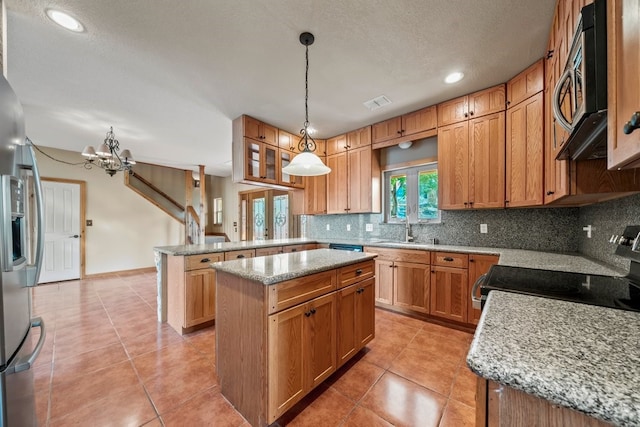 kitchen featuring decorative backsplash, a kitchen island, appliances with stainless steel finishes, hanging light fixtures, and a peninsula