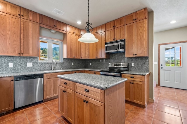 kitchen featuring hanging light fixtures, light tile patterned flooring, stainless steel appliances, and a center island